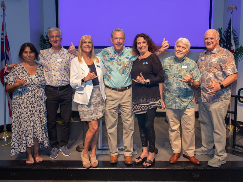 SME Honolulu networking event group photo in Waikiki Honolulu Hawaii featuring Janet Kelley and David Livingston with local business leaders wearing aloha attire and making shaka gestures during community leadership event