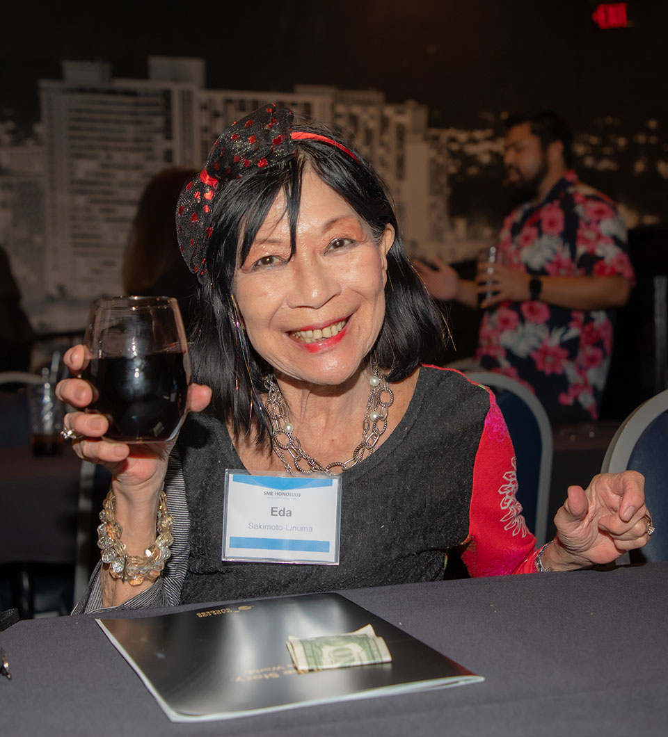 SME Honolulu member Eda Sakimoto-Linuma smiles and raises a glass during a networking event.