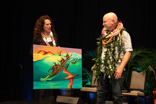 SME Honolulu SPOY banquet event award presentation with honoree receiving artwork on stage in Waikiki Honolulu Hawaii, wearing lei for Salesperson of the Year recognition, leadership achievement, and business community celebration