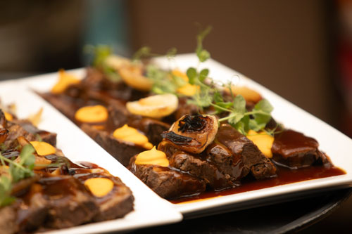 Gourmet plated dish with glazed meat and vegetables at SME Honolulu SPOY banquet event in Waikiki Honolulu Hawaii, featuring fine dining catering, hospitality, and business networking