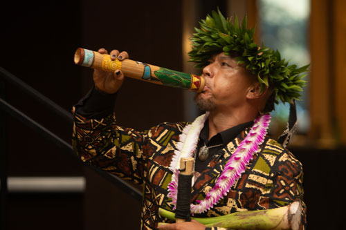 Hawaiian cultural performer blowing ceremonial pū at SME Honolulu SPOY banquet event in Waikiki Honolulu Hawaii, wearing traditional attire and maile lei, featuring Hawaiian ceremony, cultural heritage, and community engagement