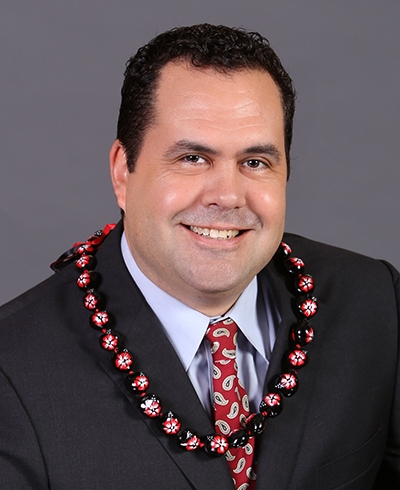 Chad Adams, SME Honolulu Board of Directors member, in a professional portrait with a teal background.