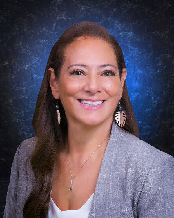 Marie Villa, Secretary of SME Honolulu, wearing a gray blazer and leaf earrings in a professional headshot.